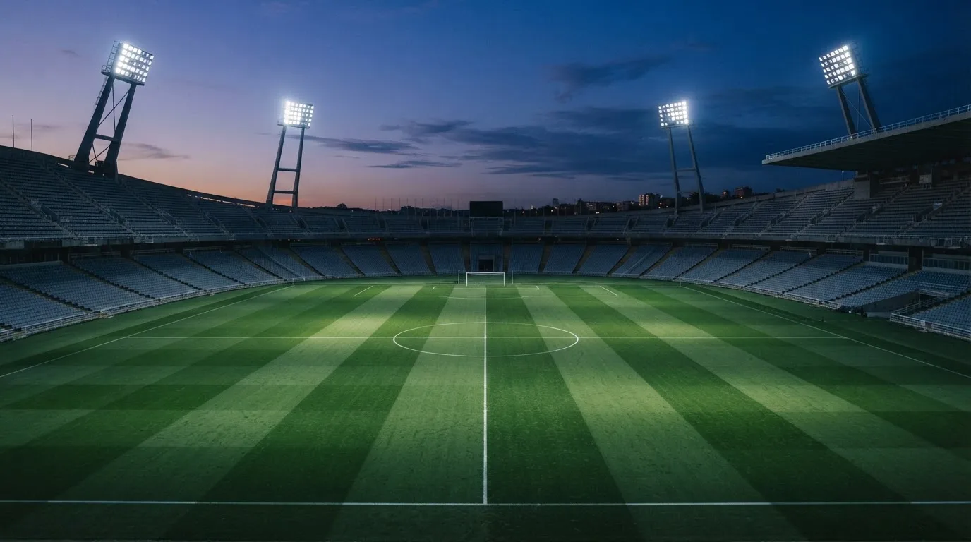 Een leeg voetbalstadion met lichtmasten bij schemering