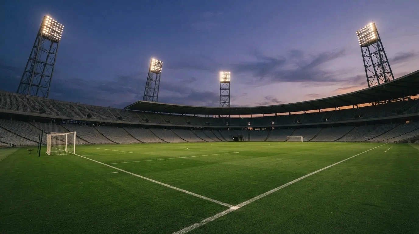Een leeg voetbalstadion met lichtmasten bij schemering