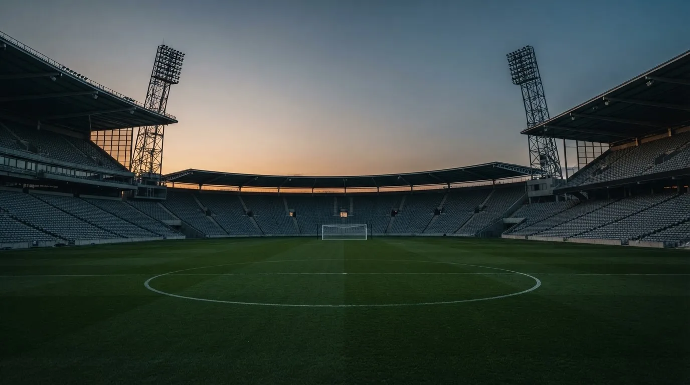 Een leeg voetbalstadion met lichtmasten bij schemering