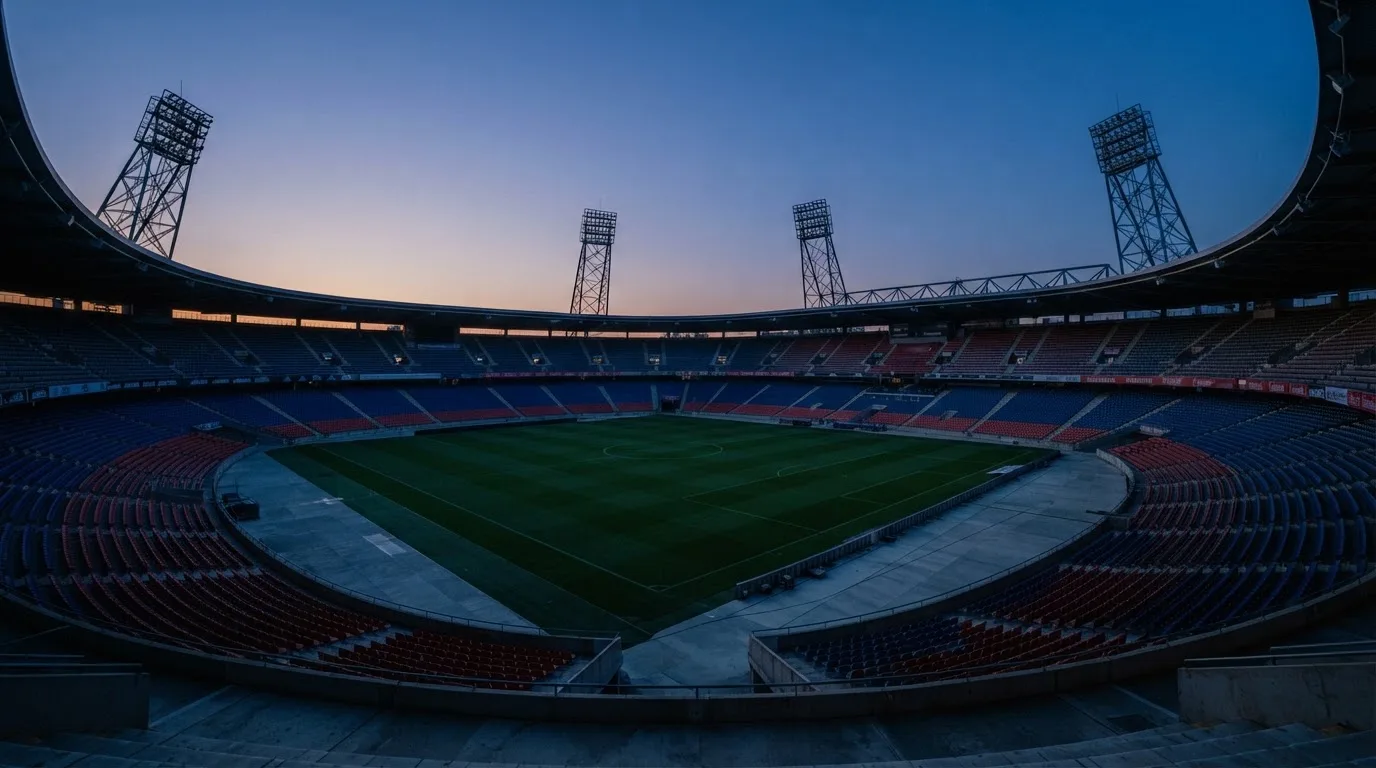 Een leeg voetbalstadion met lichtmasten bij schemering