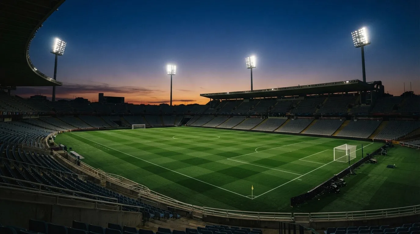 Een leeg voetbalstadion met lichtmasten bij schemering