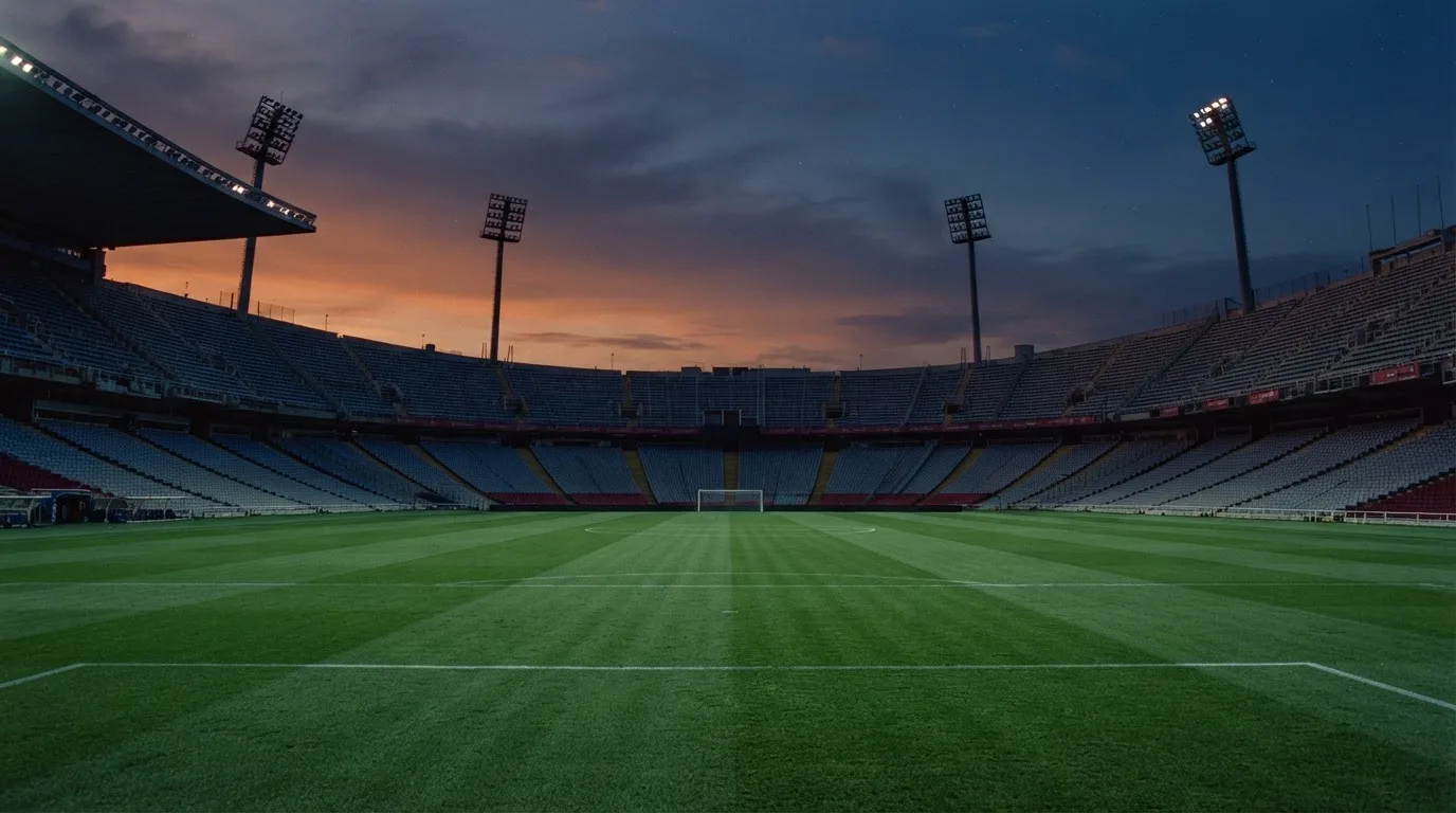 Een leeg voetbalstadion met lichtmasten bij schemering