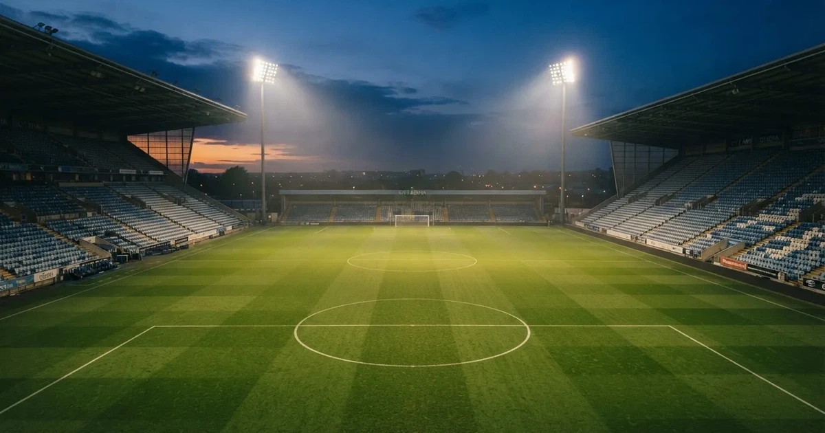 Een leeg voetbalstadion met lichtmasten bij schemering