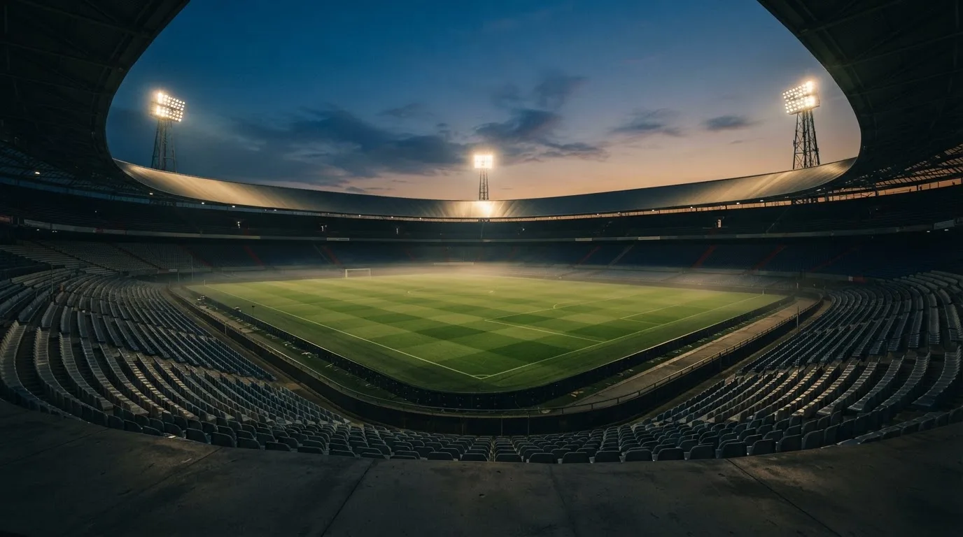 Een leeg voetbalstadion met lichtmasten bij schemering