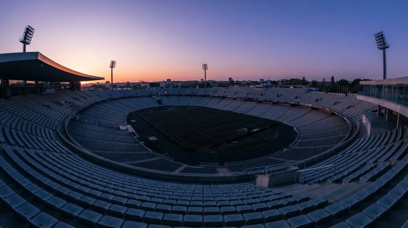Een leeg voetbalstadion met lichtmasten bij schemering