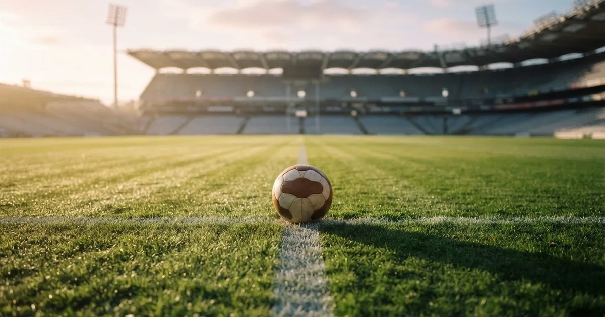 Een voetbal op de middenstip van een grasveld in het ochtendlicht