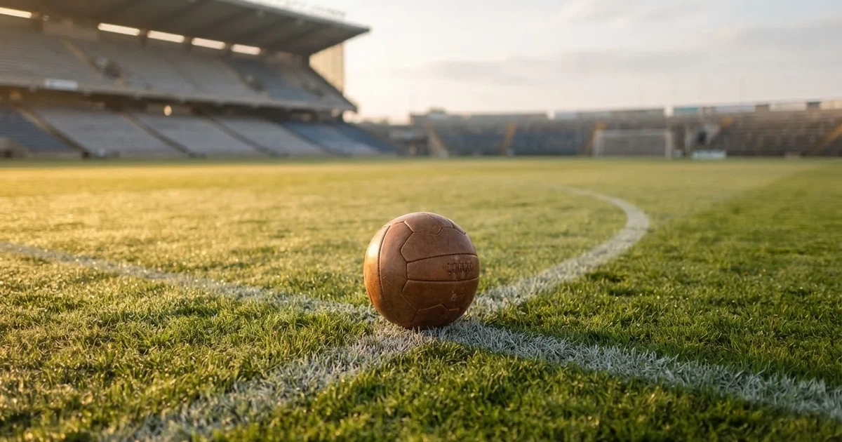 Een voetbal op de middenstip van een grasveld in het ochtendlicht