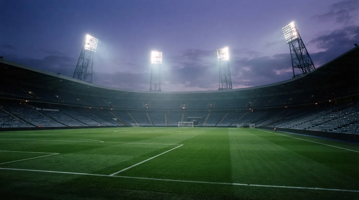 Een leeg voetbalstadion met lichtmasten bij schemering