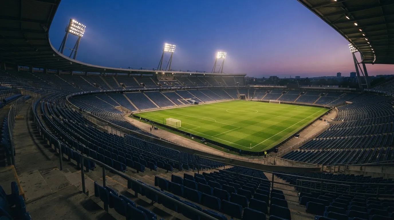 Een leeg voetbalstadion met lichtmasten bij schemering
