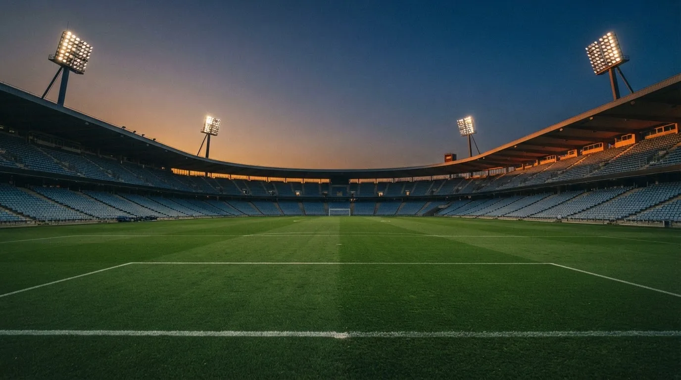 Een leeg voetbalstadion met lichtmasten bij schemering